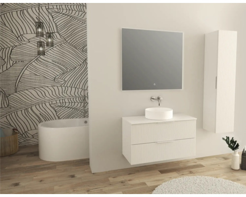 Helles Badezimmer mit Waschtischunterschrank, Aufsatzwaschbecken, Spiegel, Hochschrank und Badewanne vor einer gemusterten Wand