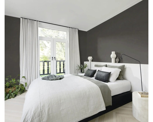 Helles Schlafzimmer mit Doppelbett, Vorhängen und Zimmerpflanzen