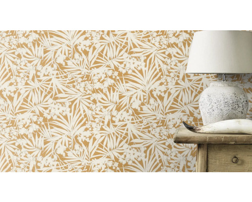 Nahaufnahme von einer Wand mit botanischer Tapete, die eine Lampe und ein Holzmöbelstück teilweise verdeckt.