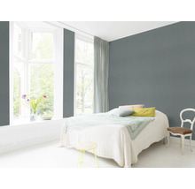 Helles Schlafzimmer mit Bett, Stuhl und grauer Wand
