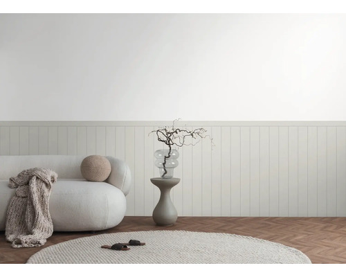 Helle Inneneinrichtung mit Sofa, Beistelltisch und dekorativen Elementen vor einer Wandvertäfelung.