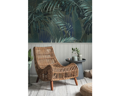 Dekoratives Zimmer mit Dschungel-Tapete und einem Rattansessel