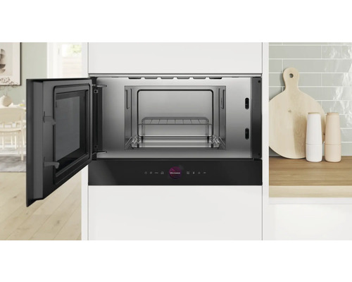 Eingebaute Mikrowelle mit geöffneter Tür in einer Küche.