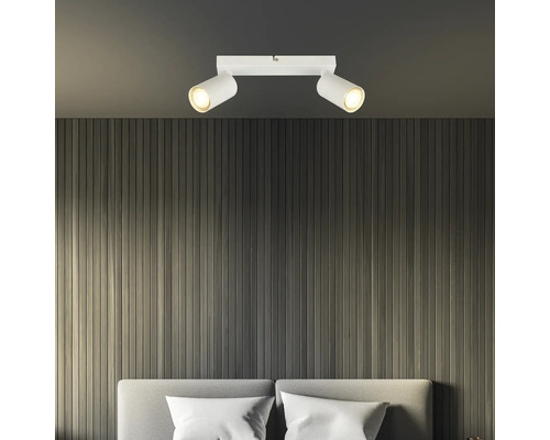 Zwei weiße LED-Deckenstrahler über einem Bett.