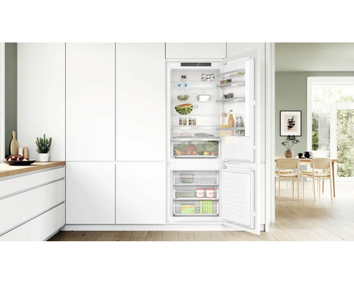 Integrierter Kühlschrank mit geöffneter Tür, gefüllt mit Lebensmitteln in einer hellen Küche