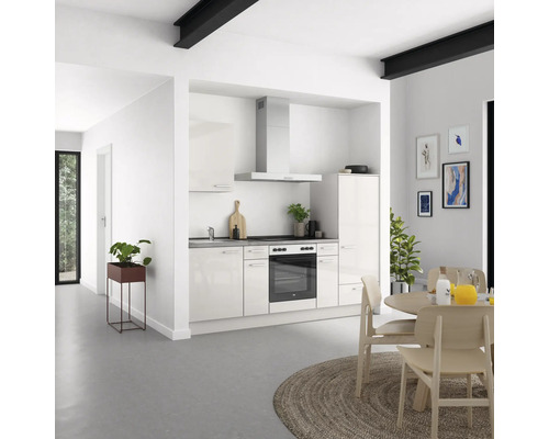 Helle Küche mit Einbauschränken, Spüle, Herd, Dunstabzugshaube und Esstisch in einem modernen Wohnraum.