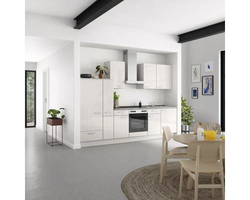 Helle Küche mit weißen Schränken, Spüle, Herd und Dunstabzugshaube in einem modernen Wohnraum.