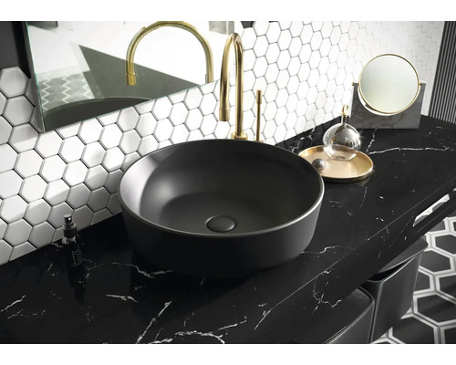 Waschbecken auf Arbeitsplatte im Badezimmer mit Armatur, Spiegel und sechseckigen Fliesen