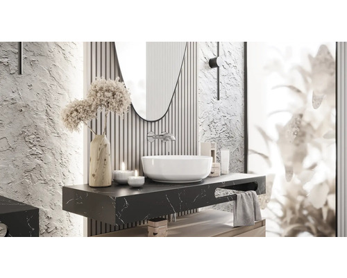 Badezimmergestaltung mit Waschbecken, Spiegel und dekorativen Elementen auf einer dunklen Marmorplatte