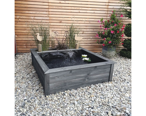 Quadratischer Teich aus Holz mit Wasserspiel und Seerosen im Garten.