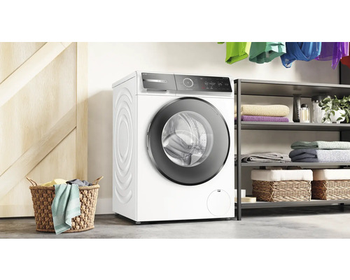 Waschmaschine in einem hellen Waschraum mit Regalen und Wäschekorb