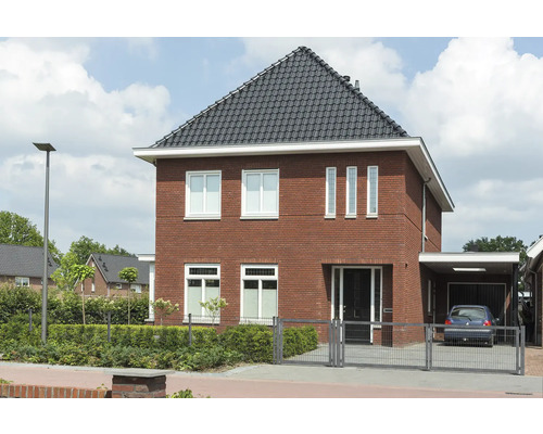 Ansicht eines Wohnhauses mit Ziegelfassade, dunklem Dach und angrenzendem Carport.