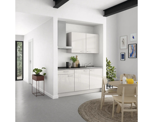 Moderne Küche mit Küchenzeile, Dunstabzugshaube und Esstisch in einem hellen Raum.