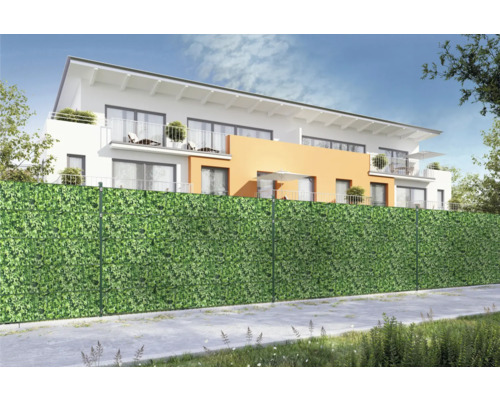 Sichtschutzzaun mit Blattmuster vor einem Wohnhaus.