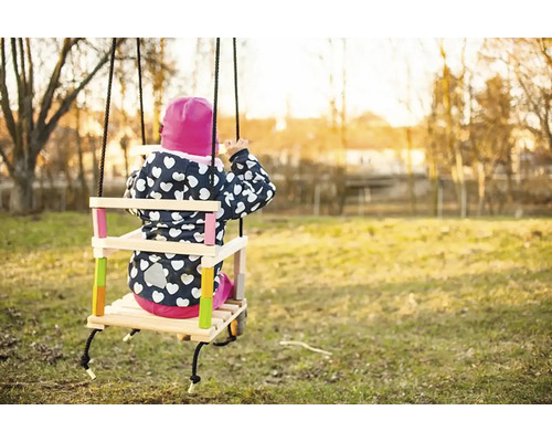 Kind auf einer Holzschaukel im Garten
