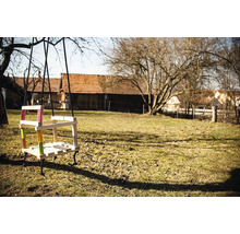 Holzschaukel mit farbigen Akzenten im Garten