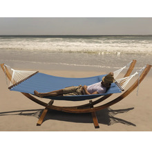 Mann entspannt in einer blauen Hängematte mit Holzgestell am Strand