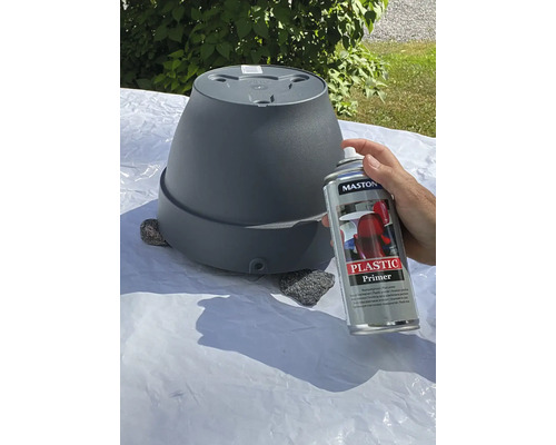 Eine Person sprüht mit Kunststoffprimer eine Blumentopf.