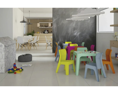 Kinderspielzimmer mit bunten Tischen und Stühlen, Spielzeug und Sitzsack.