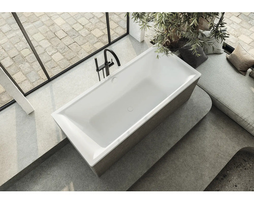 Freistehende Badewanne in einem hellen Badezimmer mit Fenster und Sitzbereich