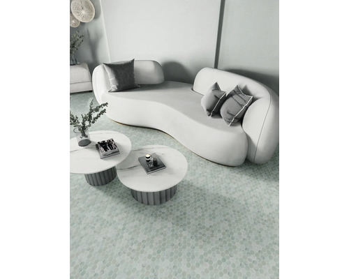 Helle Szene mit geschwungenem Sofa, Kissen und runden Tischen auf gemustertem Boden