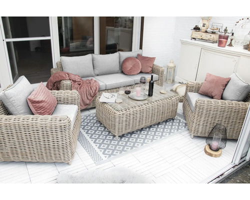 Terrasse mit Rattansitzgruppe, bestehend aus Sofa, Sessel und Tisch, dekoriert mit Kissen und Teppich