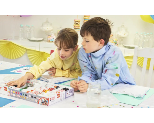 Zwei Kinder bemalen T-Shirts mit einem Textilfarben Set an einem Tisch.