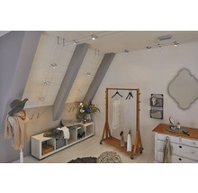 Dachgeschosszimmer mit Kleiderständer, Kommode, Sitzbank und einem Seilsystem mit Strahlern zur Beleuchtung.