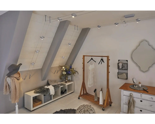 Dachgeschosszimmer mit Kleiderständer, Kommode, Sitzbank und einem Seilsystem mit Strahlern zur Beleuchtung.