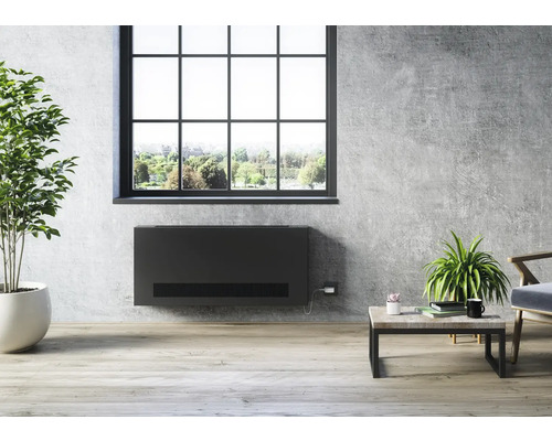 Heller Raum mit einem schwarzen Wandheizkörper unter einem Fenster, Pflanzen und Couchtisch