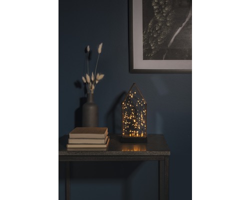 Dekoratives Arrangement mit LED-Leuchte, Vase, Büchern und gerahmtem Bild auf einem Tisch