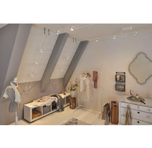 Ein Dachzimmer mit Kleiderständer, Kommode und Seilsystem Leuchte.