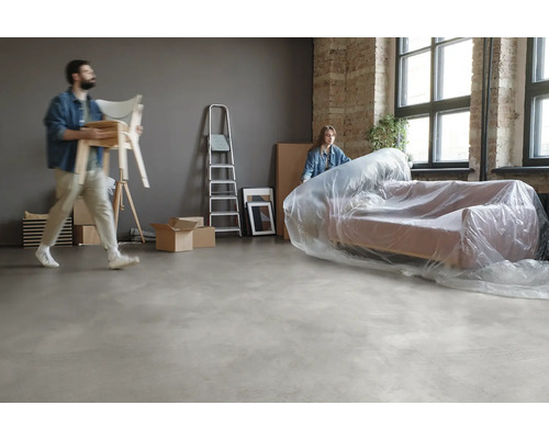 Umzugsszene mit Sofa unter Schutzfolie, Leiter und Umzugskartons in einem hellen Raum.