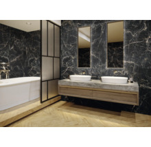 Badezimmer mit Badewanne, Waschtisch, Waschbecken und Spiegeln vor Wandfliesen in Marmoroptik