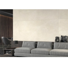Heller Wohnraum mit großformatigen Wandfliesen, grauem Sofa und dunklen Holzdetails