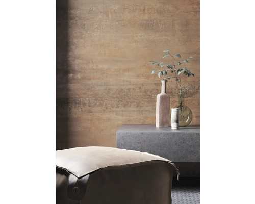 Raumansicht mit einem Pouf, einem Beistelltisch und Dekorationsgegenständen vor einer gemusterten Wand