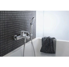 Badezimmerarmatur mit Handbrause an einer Wand mit Mosaikfliesen über einer Badewanne
