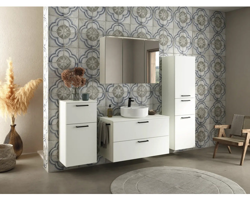 Badezimmeransicht mit weißem Waschtisch, Spiegelschrank und Hochschrank vor gemusterter Wand