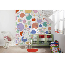 Dekoriertes Kinderzimmer mit Kinderbett, Schaukelstuhl und Tapete mit Cartoon-Motiven