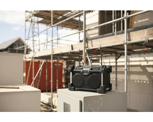 Baustellenradio vor einem unfertigen Gebäude mit Baugerüst