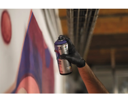 Eine Person sprüht mit einer Sprühdose Farbe auf eine Wand und gestaltet ein Graffiti.