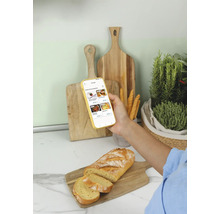 Brotlaib und Brotscheiben auf Holzbrett neben Smartphone mit App-Anzeige