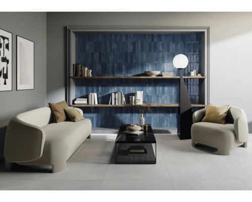 Wohnzimmer mit Sofa, Sessel, Couchtisch, Bücherregal und blauen Wandfliesen