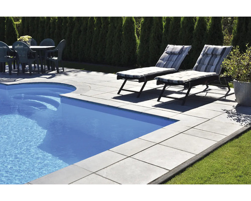 Schwimmbadbereich mit Becken, Steinplatten, Liegestühlen und Gartentisch mit Stühlen