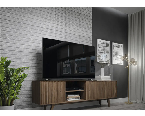 Wohnzimmer mit Fernseher auf Holzschrank vor einer Ziegelwand.