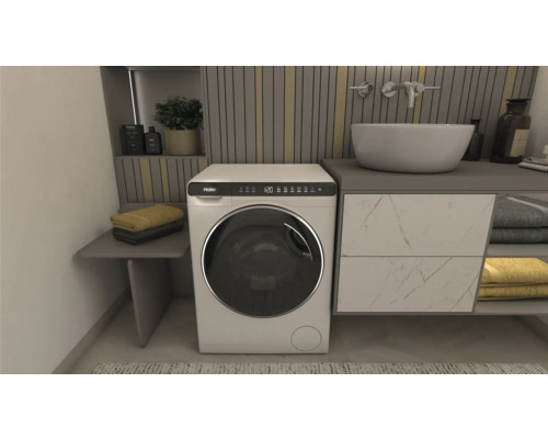 Badezimmer mit Waschbecken, Waschmaschine der Marke Haier und Handtüchern