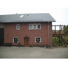 Ansicht eines zweistöckigen Hauses mit Ziegeldach und Holzterrasse