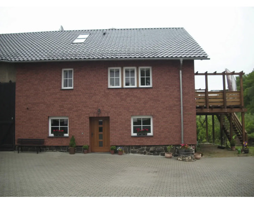 Ansicht eines zweistöckigen Hauses mit Ziegeldach und Holzterrasse