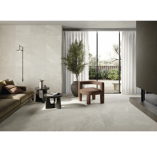 Wohnzimmer mit Fliesenboden und Wandfliesen in Marmoroptik, Sofa, Sesseln und Zimmerpflanze.