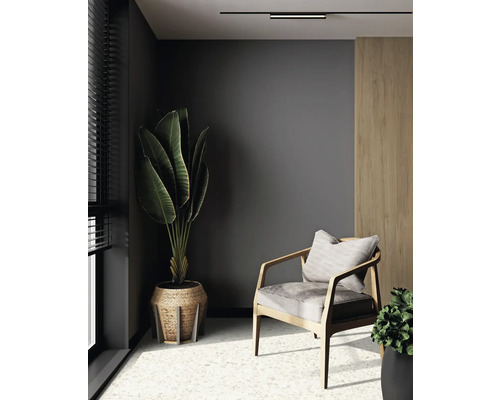 Raumszene mit Sessel, Zimmerpflanzen und Deckenleuchte für eine gemütliche Atmosphäre.